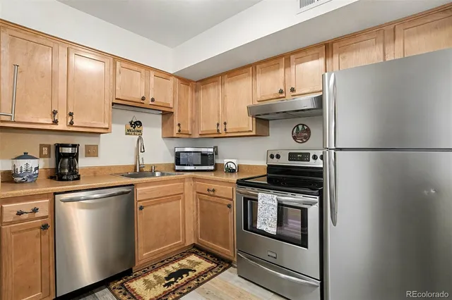 a kitchen with stainless steel appliances granite countertop a refrigerator sink stove and cabinets