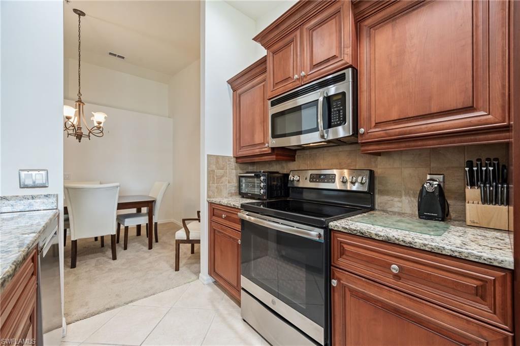 2770 Cypress Trace Circle, Unit 2425 Naples, FL 34119 - Photo 11 of 35 a kitchen with granite countertop a stove top oven microwave and cabinets
