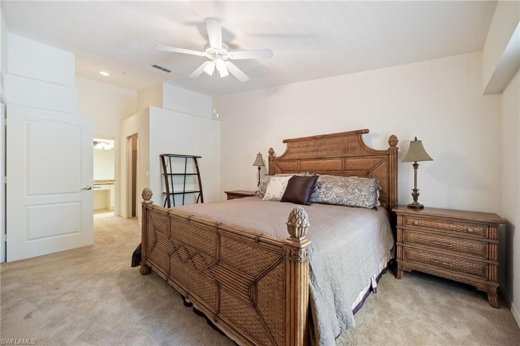 2770 Cypress Trace Circle, Unit 2425 Naples, FL 34119 - Photo 15 of 35 a bedroom with a bed and a chandelier