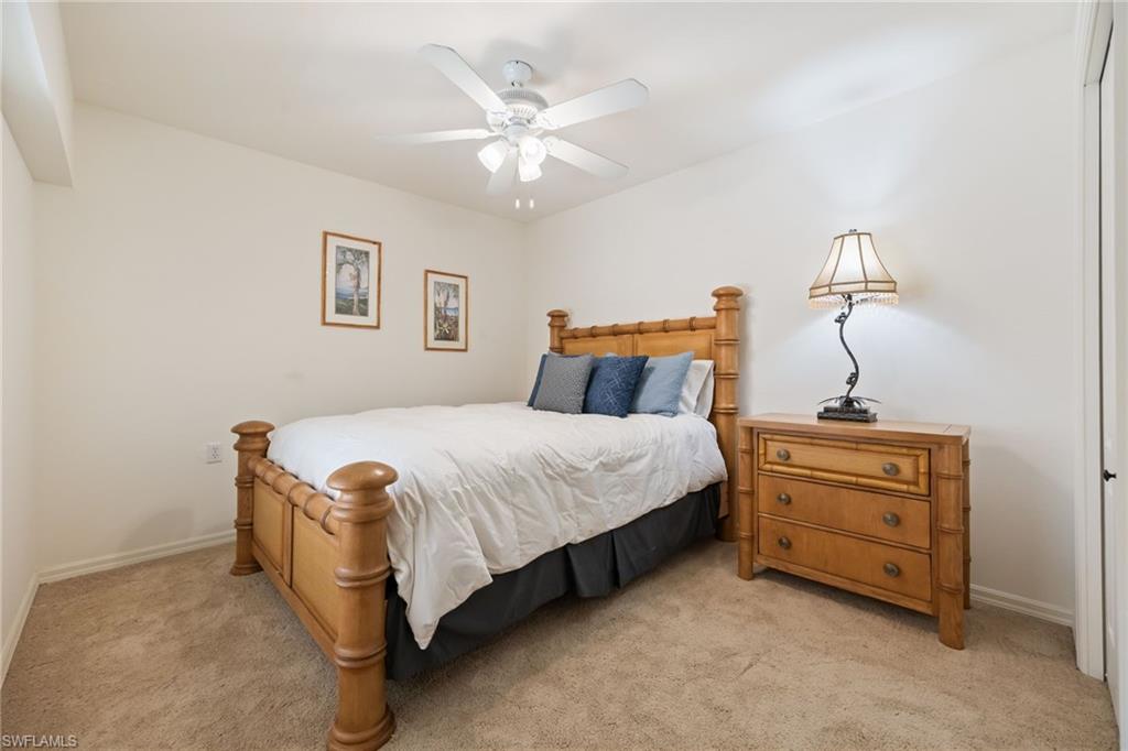 2770 Cypress Trace Circle, Unit 2425 Naples, FL 34119 - Photo 20 of 35 a bedroom with a bed and a chandelier