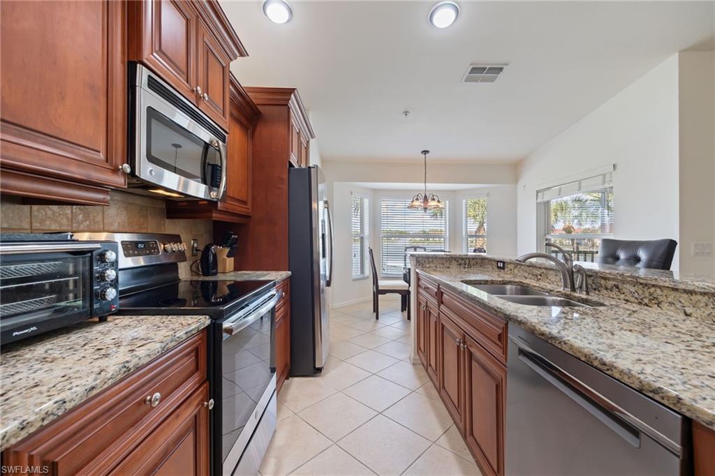 2770 Cypress Trace Circle, Unit 2425 Naples, FL 34119 - Photo 10 of 35 a kitchen with stainless steel appliances granite countertop a stove a sink and a refrigerator