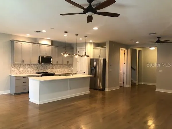 a large kitchen with a large counter top a sink stainless steel appliances and cabinets
