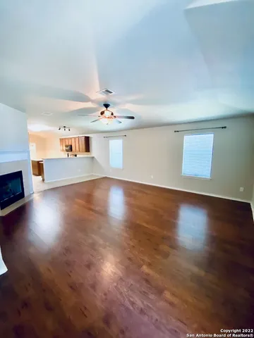 an empty room with wooden floor fireplace and windows