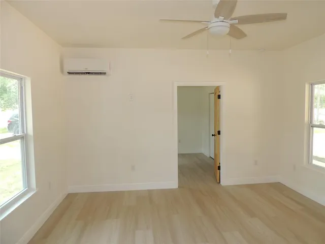an empty room with wooden floor closet and windows