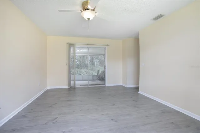 an empty room with a chandelier fan and windows