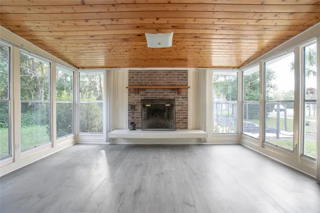 a view of an empty room with wooden floor and a fireplace