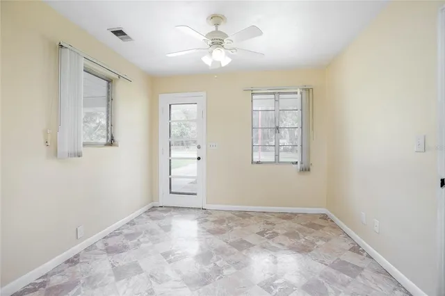 an empty room with windows and fan