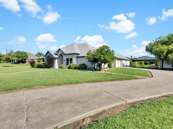a view of a house with a big yard and large trees