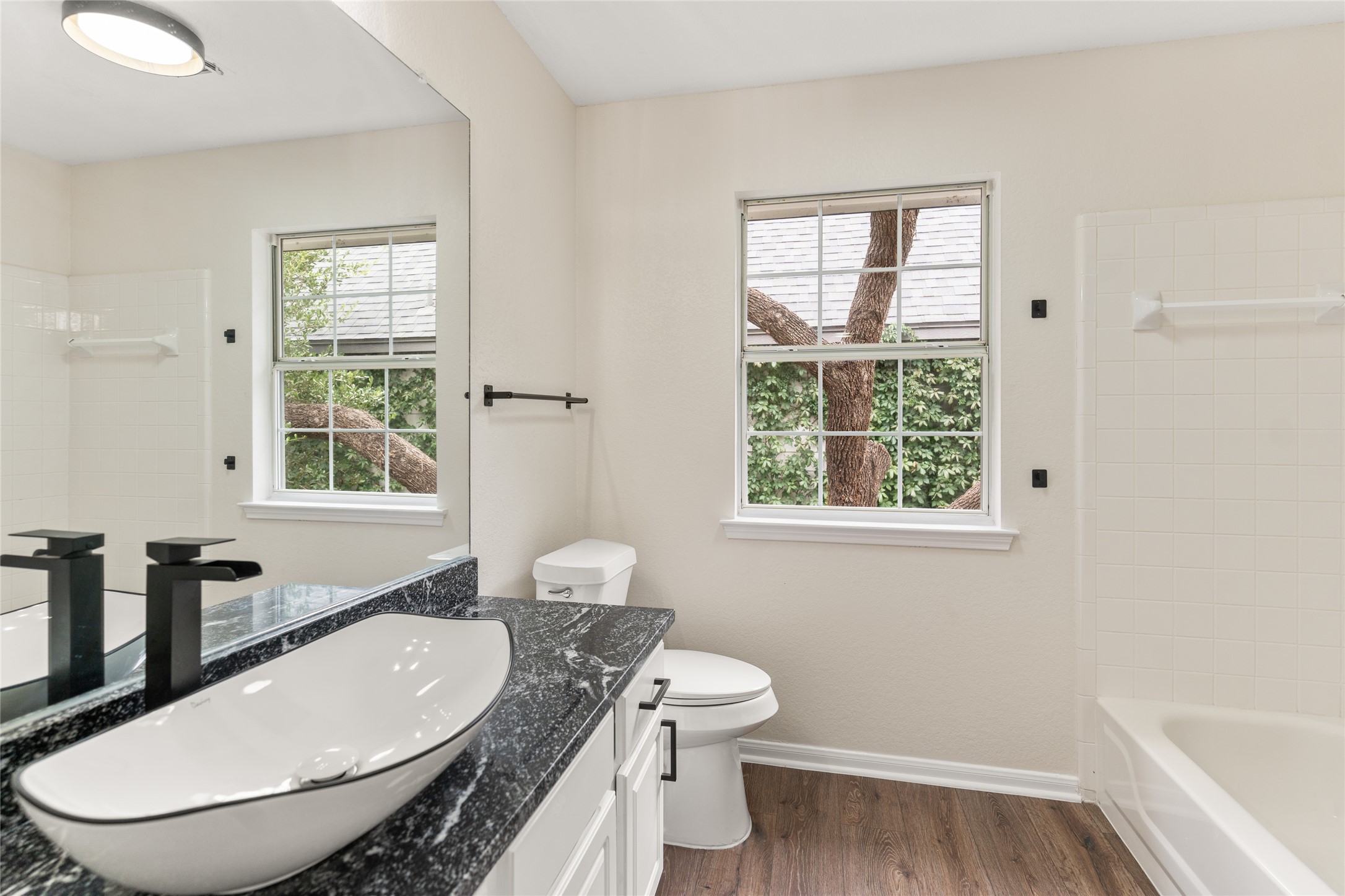 13102 Hunters Chase Drive Austin, TX 78729 - Photo 20 of 39 a bathroom with a granite countertop sink a toilet a mirror and a window