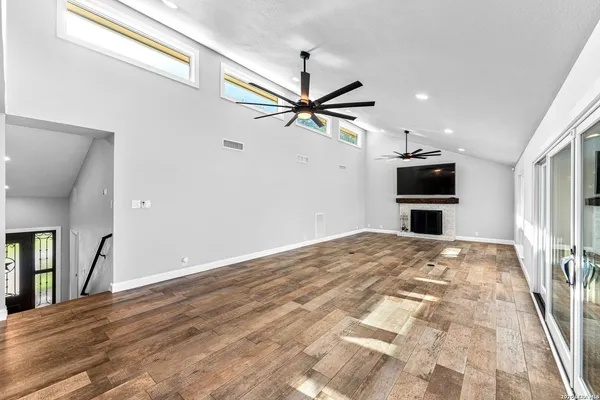 a room with stainless steel appliances kitchen island granite countertop a refrigerator a stove a sink a dining table and chairs with wooden floor