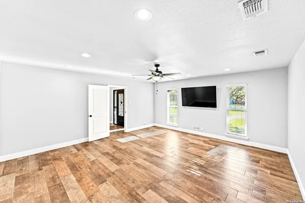 a view of a big room with wooden floor and windows