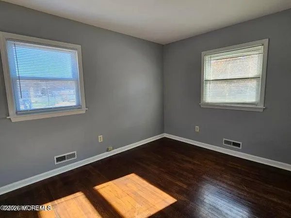 a view of a big room with wooden floor and windows