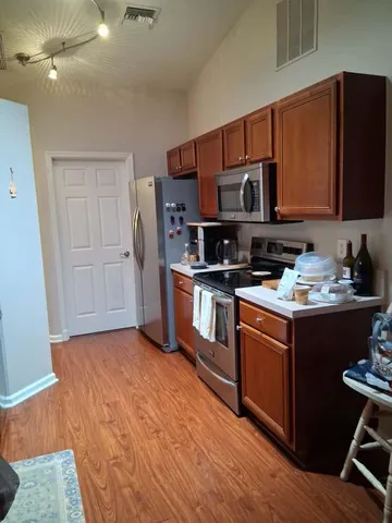 a kitchen with stainless steel appliances granite countertop a stove a sink dishwasher a microwave oven and a refrigerator with wooden floor