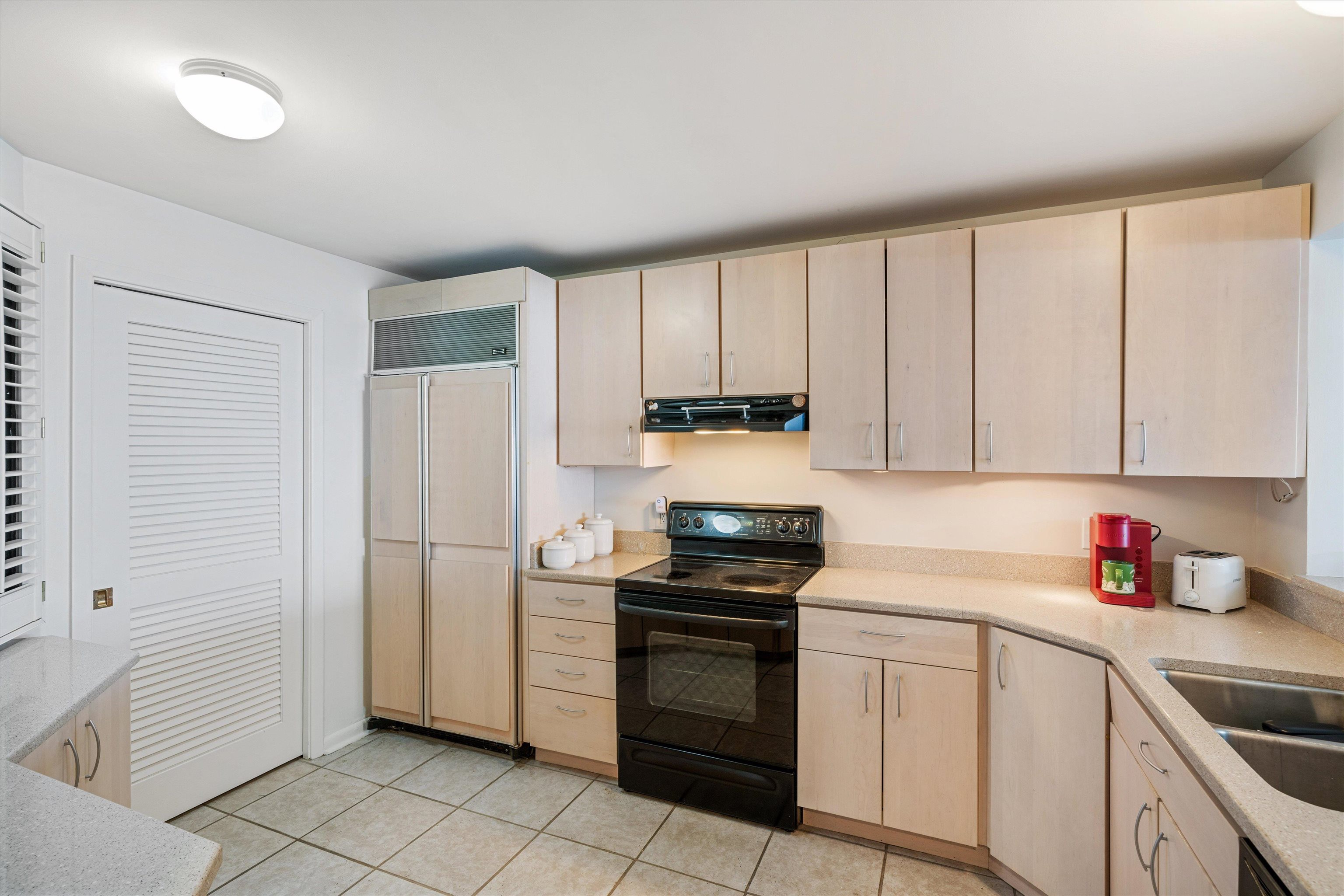 200 Wagner Street, Unit 604 Memphis, TN 38103 - Photo 11 of 36 Kitchen with light wood finish cabinetry, black range with electric stovetop, paneled built in fridge, light tile patterned floors, and light stone counters