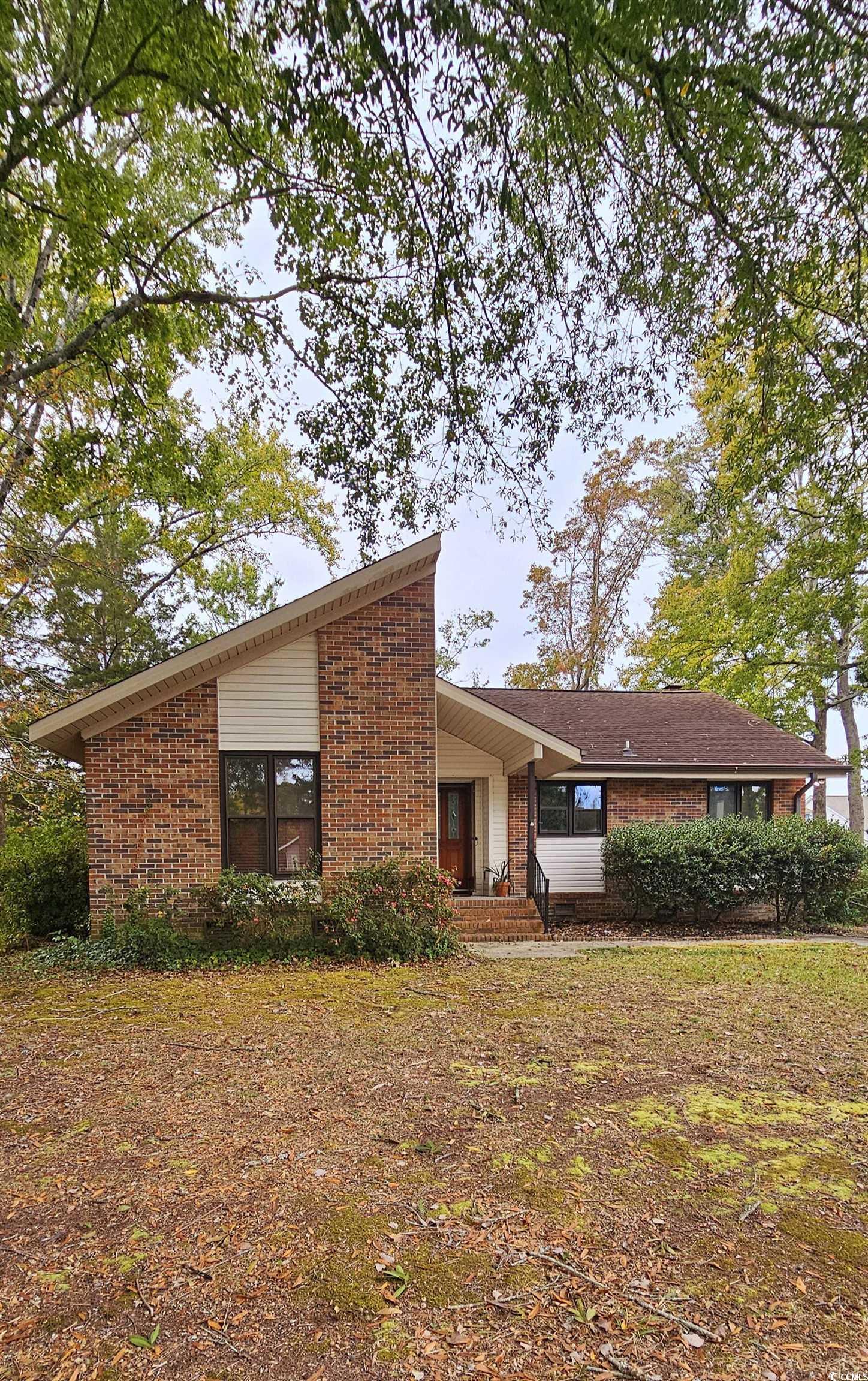 Back of house with brick siding and a lawn