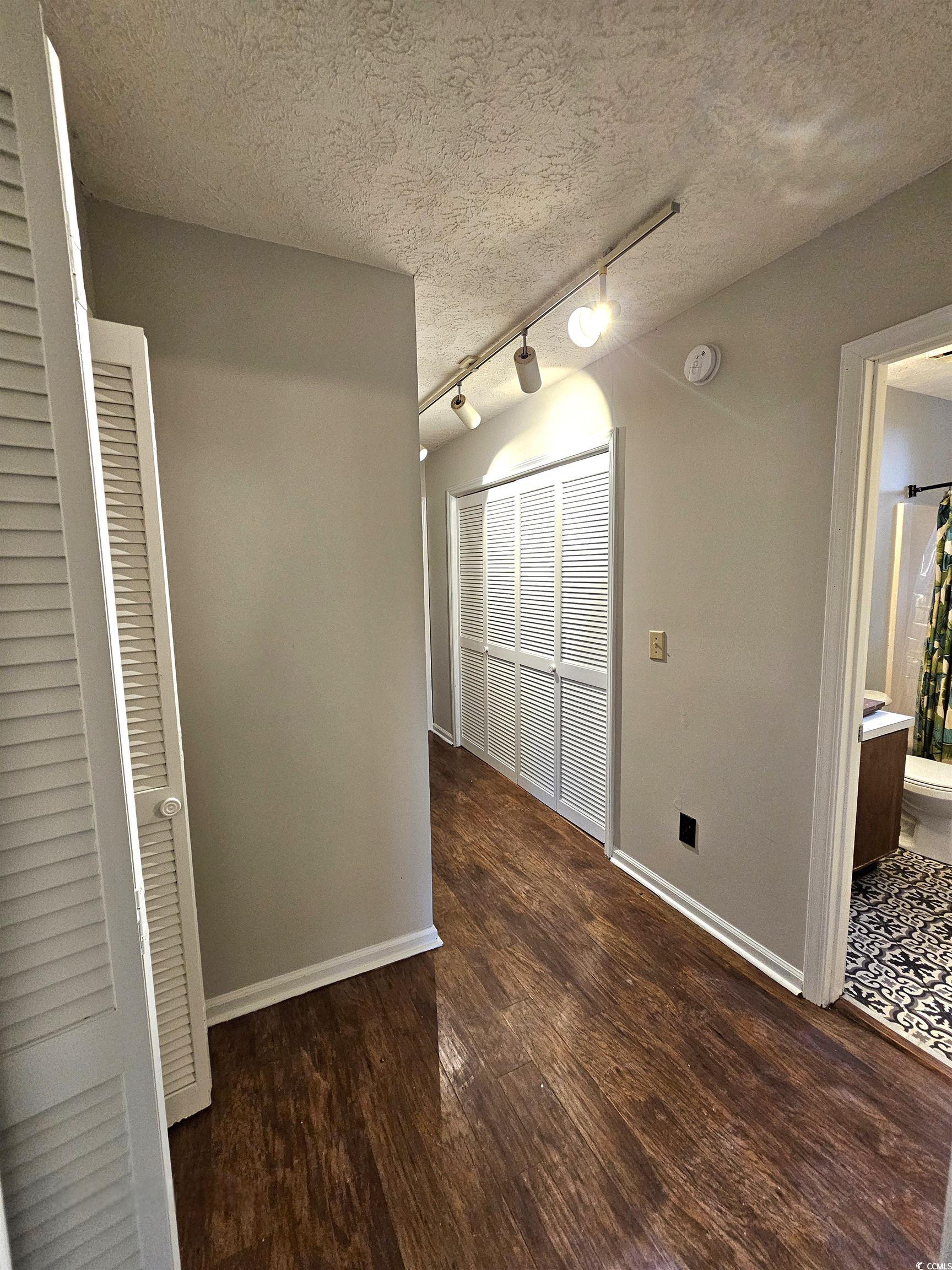117 Partridge Berry Road Myrtle Beach, SC 29579 - Photo 22 of 33 Unfurnished dining area featuring track lighting, dark wood-type flooring, and a textured ceiling