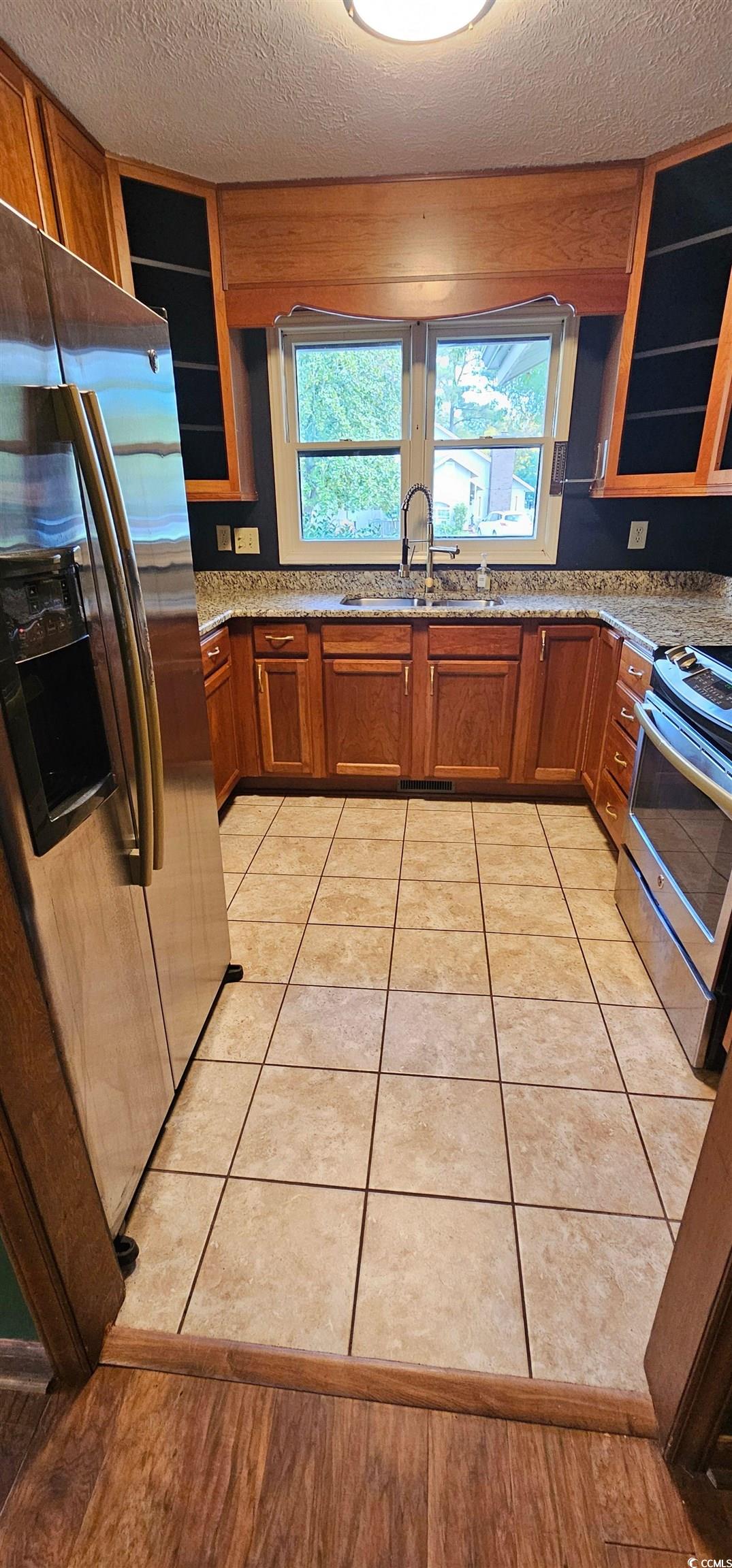 117 Partridge Berry Road Myrtle Beach, SC 29579 - Photo 8 of 33 Kitchen featuring brown cabinets, appliances with stainless steel finishes, glass insert cabinets, and a textured ceiling