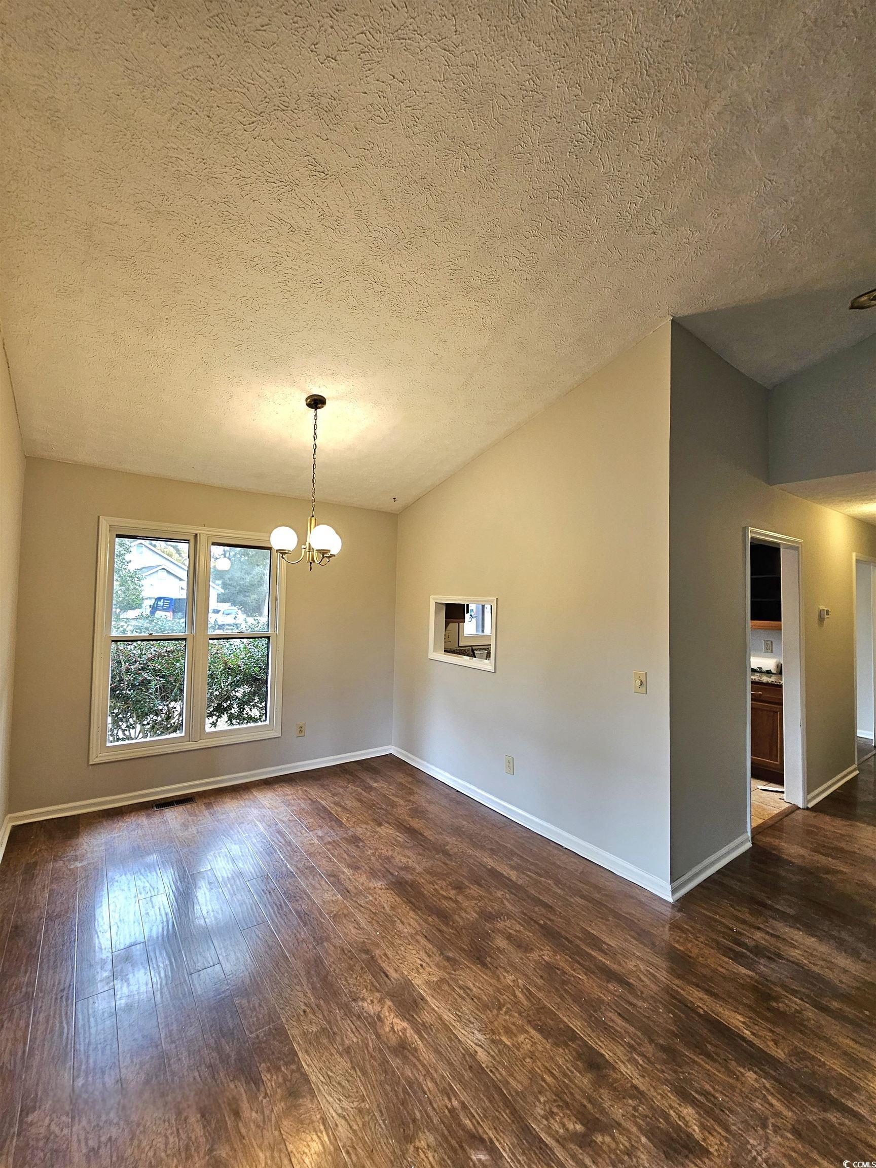 117 Partridge Berry Road Myrtle Beach, SC 29579 - Photo 9 of 33 Spare room with dark wood-type flooring, lofted ceiling, a textured ceiling, and a chandelier