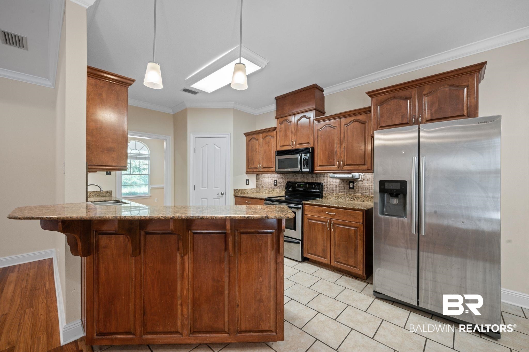 2041 Ridgeline Drive Mobile, AL 36695 - Photo 9 of 43 Kitchen with appliances with stainless steel finishes, tasteful backsplash, kitchen peninsula, hanging light fixtures, and light tile patterned floors