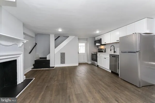 a kitchen with refrigerator and wooden floor