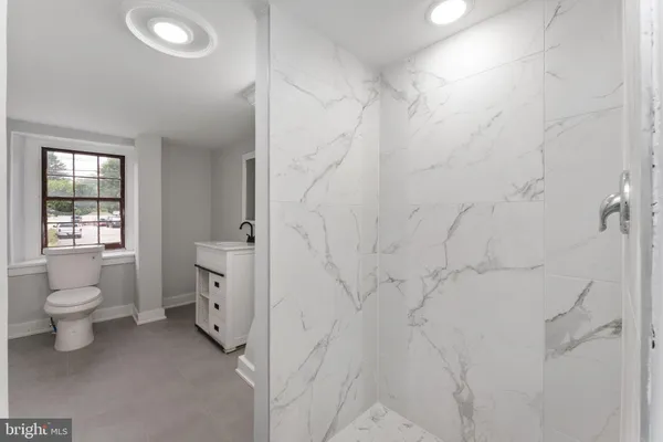 a bathroom with a granite countertop toilet a sink and a shower
