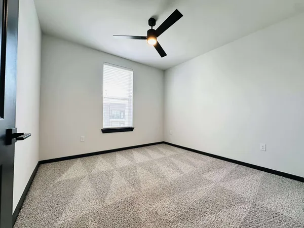 an empty room with ceiling fan and windows