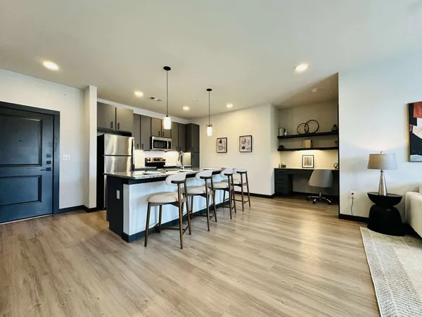 a living room with furniture and kitchen view with wooden floor