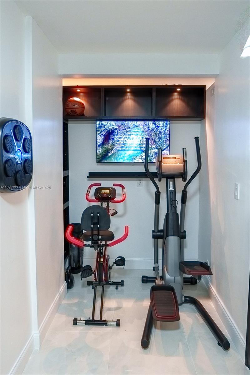 4000 Towerside Terrace, Unit 410 Miami, FL 33138 - Photo 13 of 74 a room with gym equipment and paintings on the wall