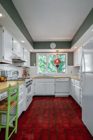 a kitchen with stainless steel appliances a white cabinets and window