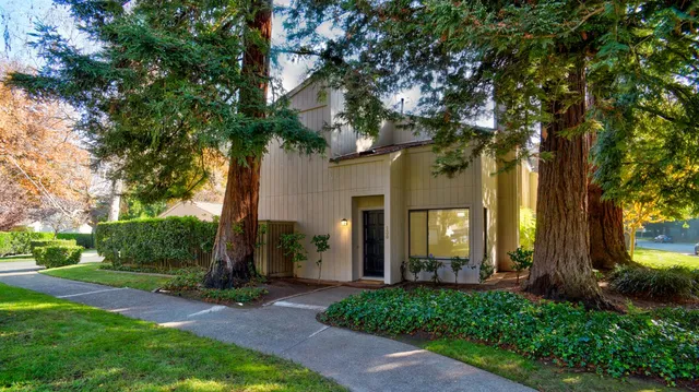 a front view of a house with a garden and trees