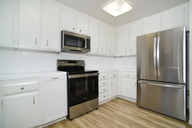 a kitchen with a refrigerator stove and white cabinets