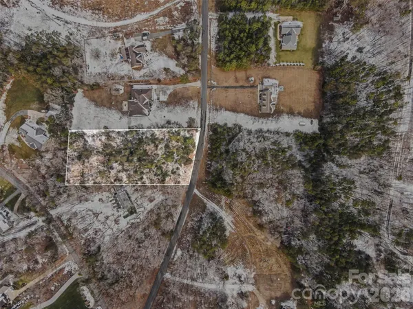 a view of a dirt yard with trees in the background