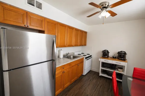 a kitchen with a refrigerator a stove cabinets and wooden floor