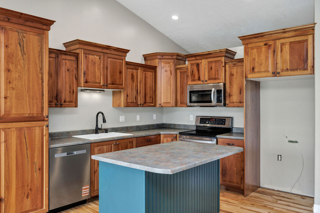 2912 South 1080th Street West Logan, UT 84321 - Photo 29 of 43 Kitchen featuring wood-finish cabinetry, stainless steel appliances, a center island with a laminate countertop, a white single-basin sink, and light-colored flooring