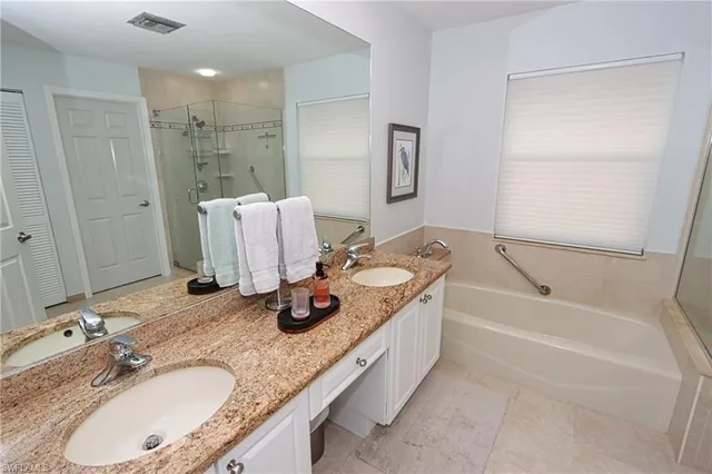 a bathroom with a granite countertop tub sink and mirror