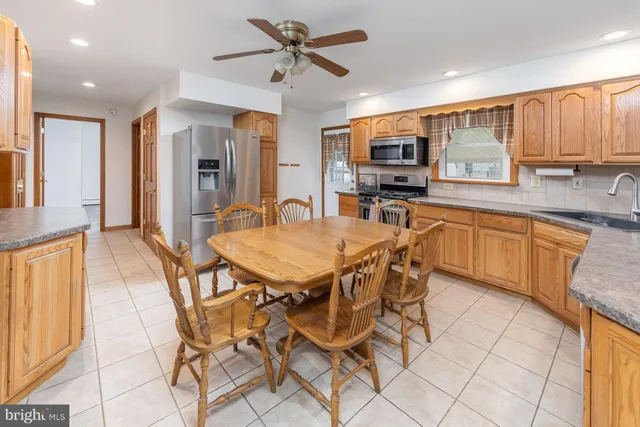 a kitchen with stainless steel appliances granite countertop a stove top oven a sink dishwasher and white cabinets with wooden floor