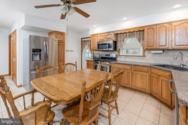 a kitchen with stainless steel appliances granite countertop a stove top oven a sink dishwasher a dining table and chairs with wooden floor