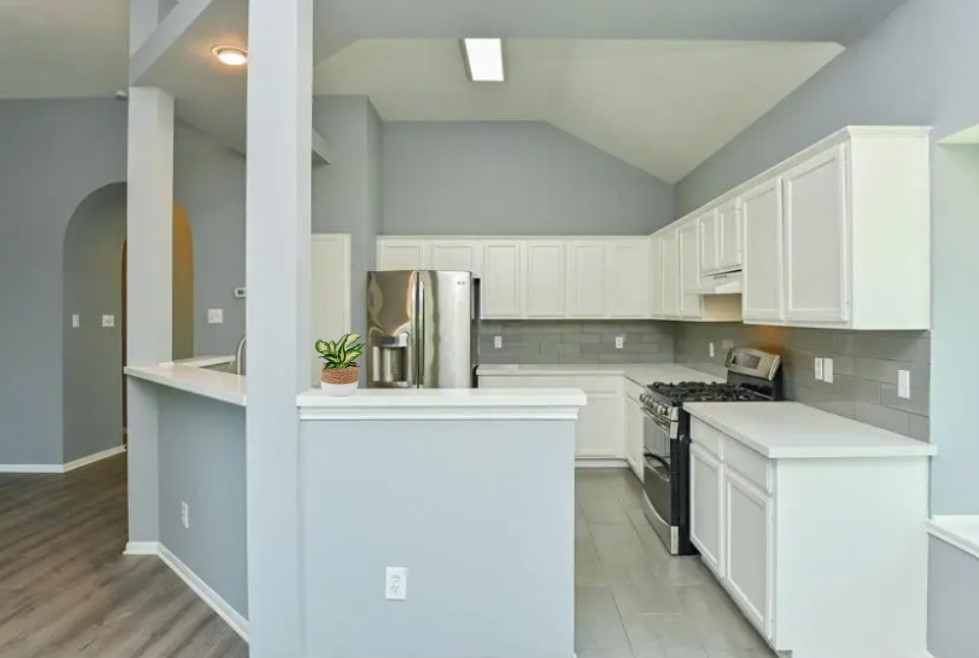 12922 Mills Bend Street Houston, TX 77070 - Photo 23 of 50 a kitchen with a stove a sink and white cabinets