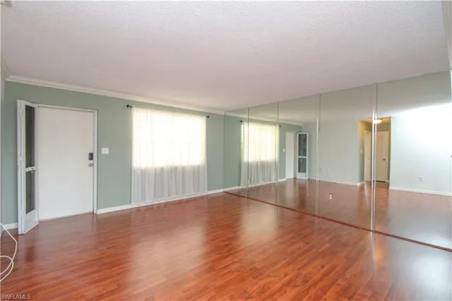 a view of an empty room with window and wooden floor