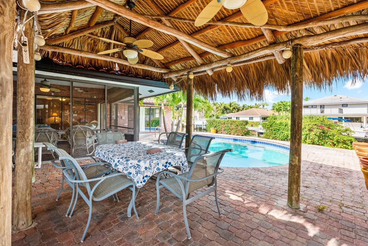 3163 Northeast 8th Avenue Boca Raton, FL 33431 - Photo 22 of 31 a view of a patio with a table and chairs under an umbrella with a patio