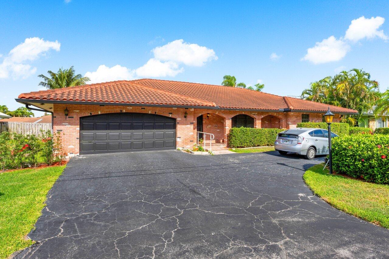 3163 Northeast 8th Avenue Boca Raton, FL 33431 - Photo 7 of 31 a front view of a house with a yard and garage