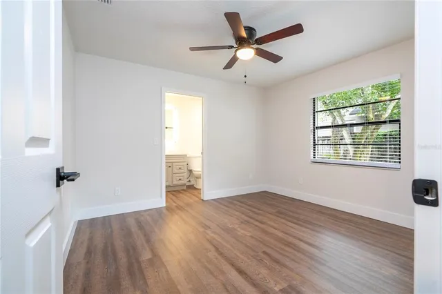 an empty room with wooden floor chandelier fan and windows