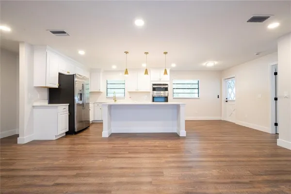 a kitchen with kitchen island white cabinets and refrigerator