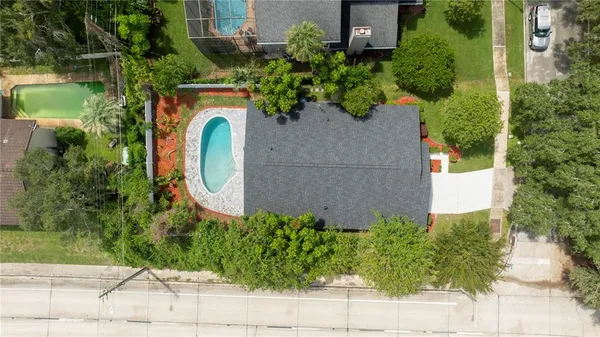 an aerial view of a house with garden space and trees all around