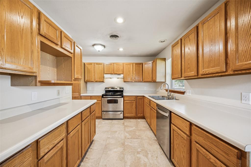 601 Ridgedale Drive Richardson, TX 75080 - Photo 8 of 26 a kitchen with stainless steel appliances granite countertop a sink dishwasher stove and refrigerator with wooden cabinets