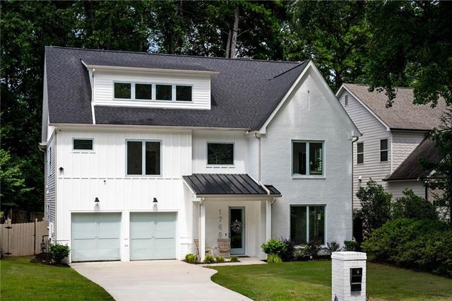 a view of a white house with large windows and a small yard