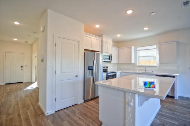a kitchen with a refrigerator a sink dishwasher and a stove with wooden floor