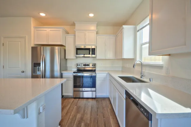 a kitchen with stainless steel appliances a sink stove refrigerator and cabinets