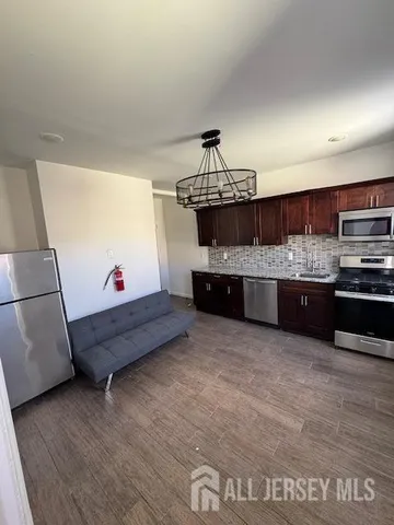 a living room with stainless steel appliances kitchen island granite countertop a refrigerator and a stove top oven
