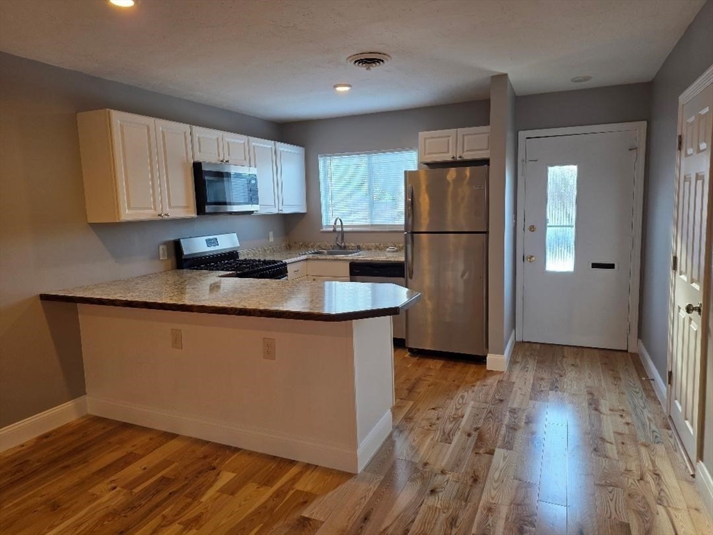 a kitchen with stainless steel appliances granite countertop a refrigerator a sink a stove a microwave and wooden floors
